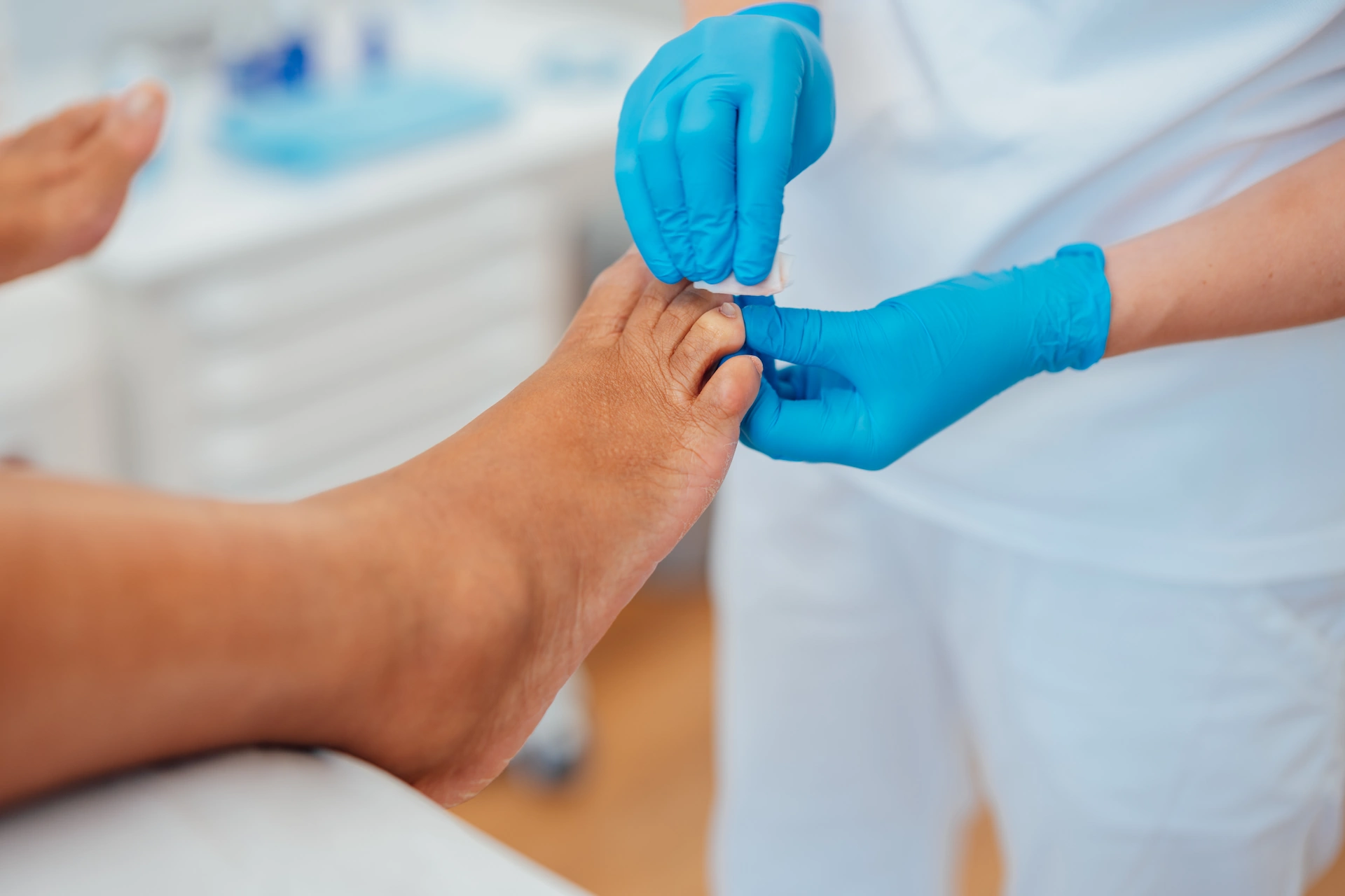 Podologin Madlen mit blauen Handschuhen behandelt den Fuss einer Patientin.